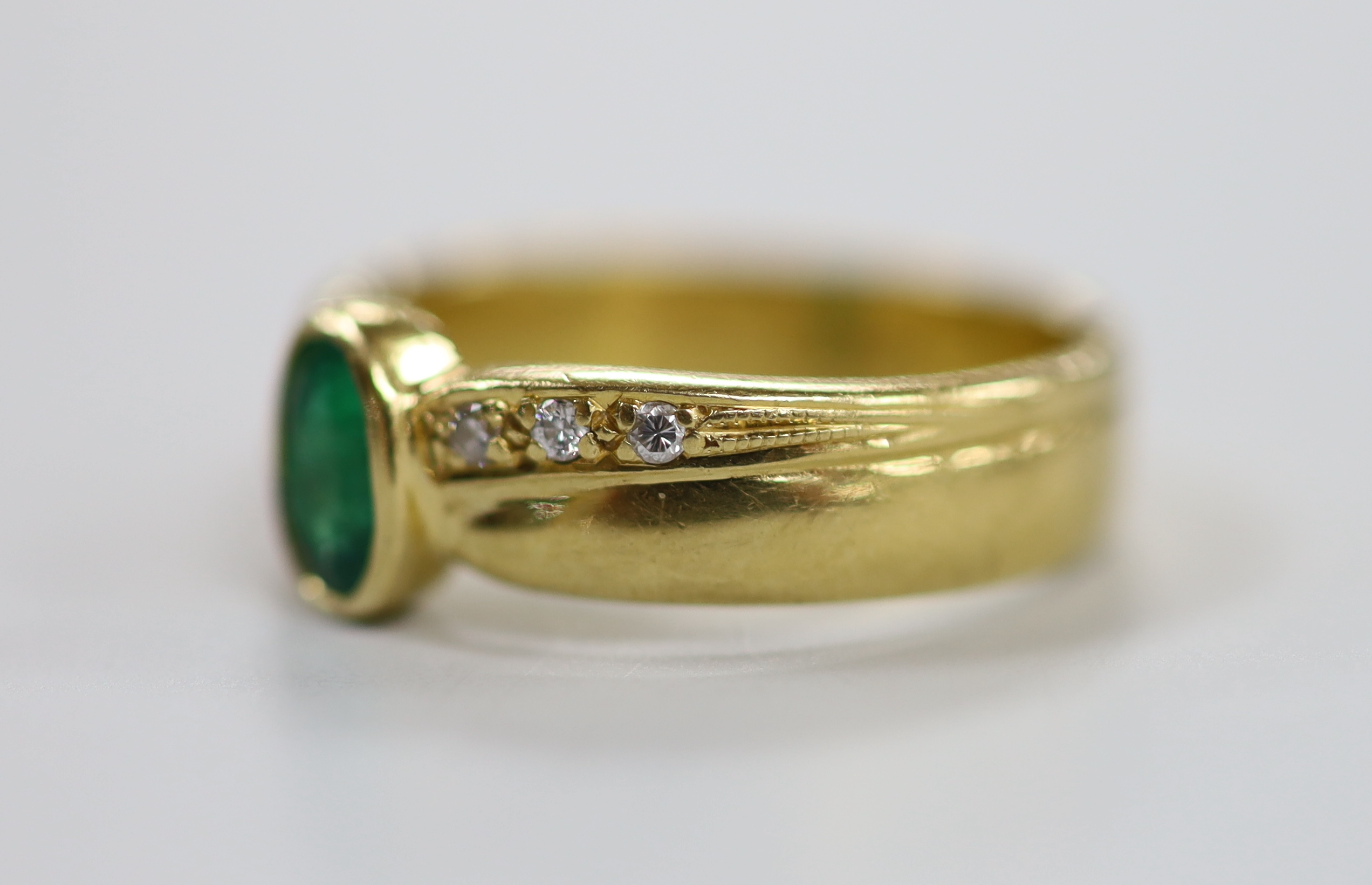 A modern 18ct gold and single stone oval cut emerald ring, with six stone diamond set shoulders, size J. gross weight 4.7 grams.